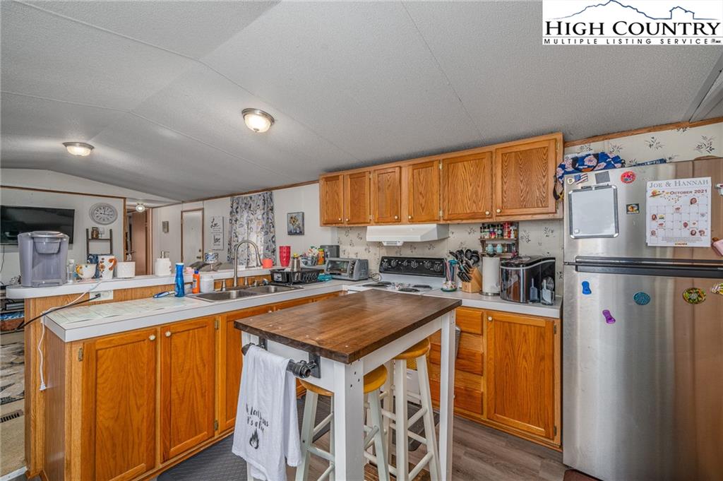 1310 Meat Camp Road Boone, NC 28607 - Photo 22 of 32 a kitchen with stainless steel appliances granite countertop a refrigerator a sink dishwasher and white cabinets with wooden floor