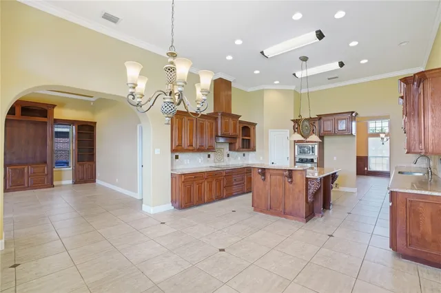 a room with kitchen island stainless steel appliances a chandelier open kitchen view