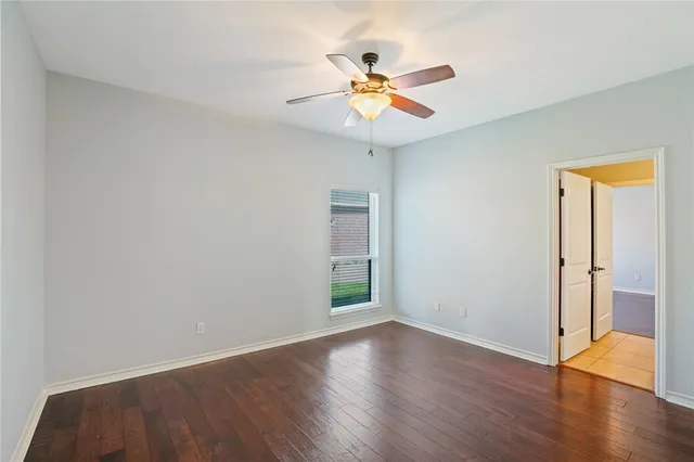 an empty room with wooden floor and a ceiling fan