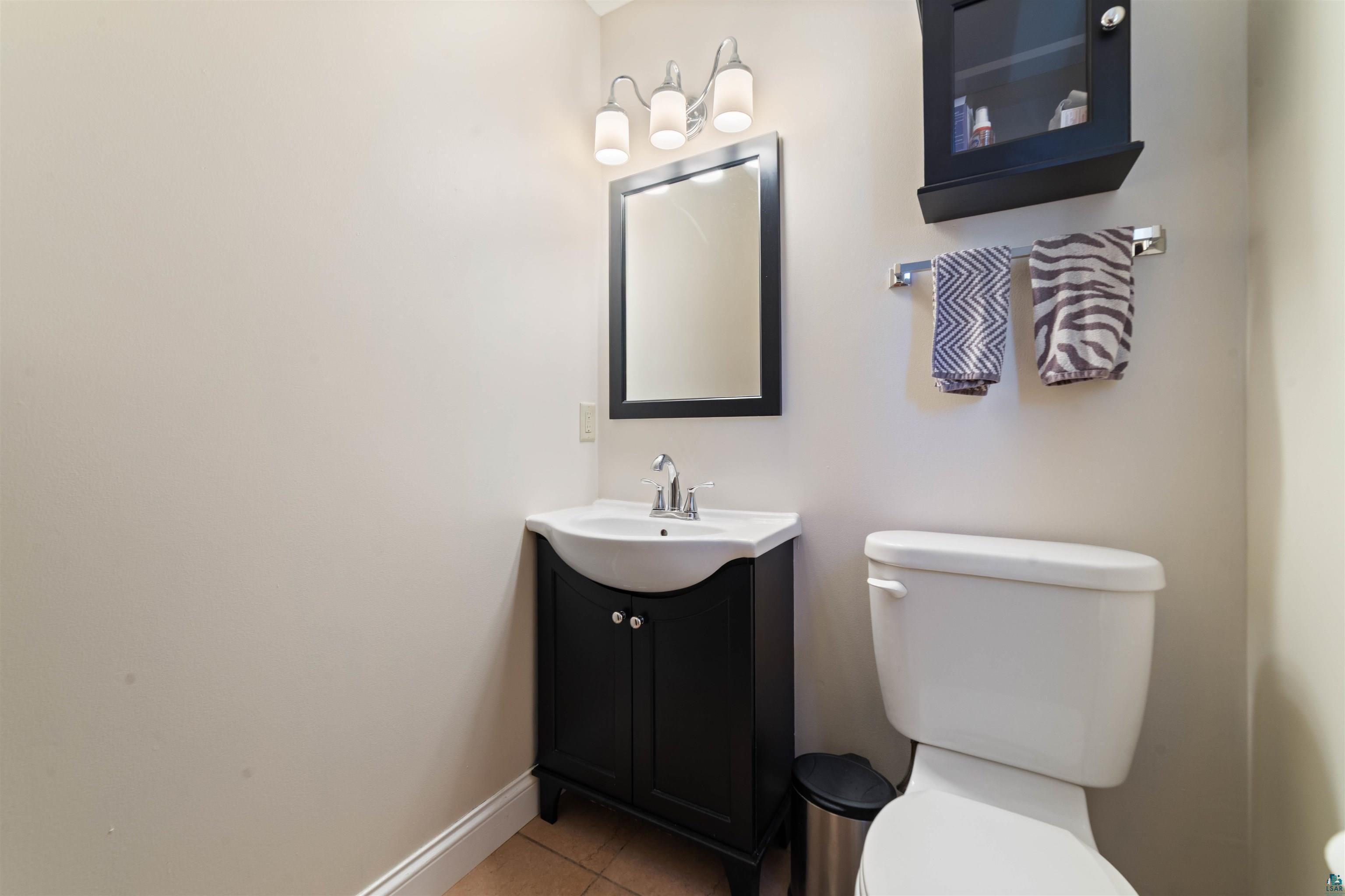 4073 Reinke Road Duluth, MN 55811 - Photo 18 of 32 Bathroom featuring a dark wood-finish vanity with an integrated basin, a framed mirror, and a three-light vanity fixture