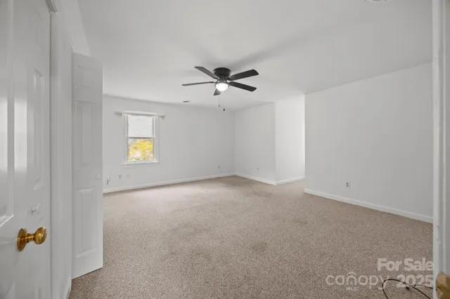 an empty room with a ceiling fan and carpet