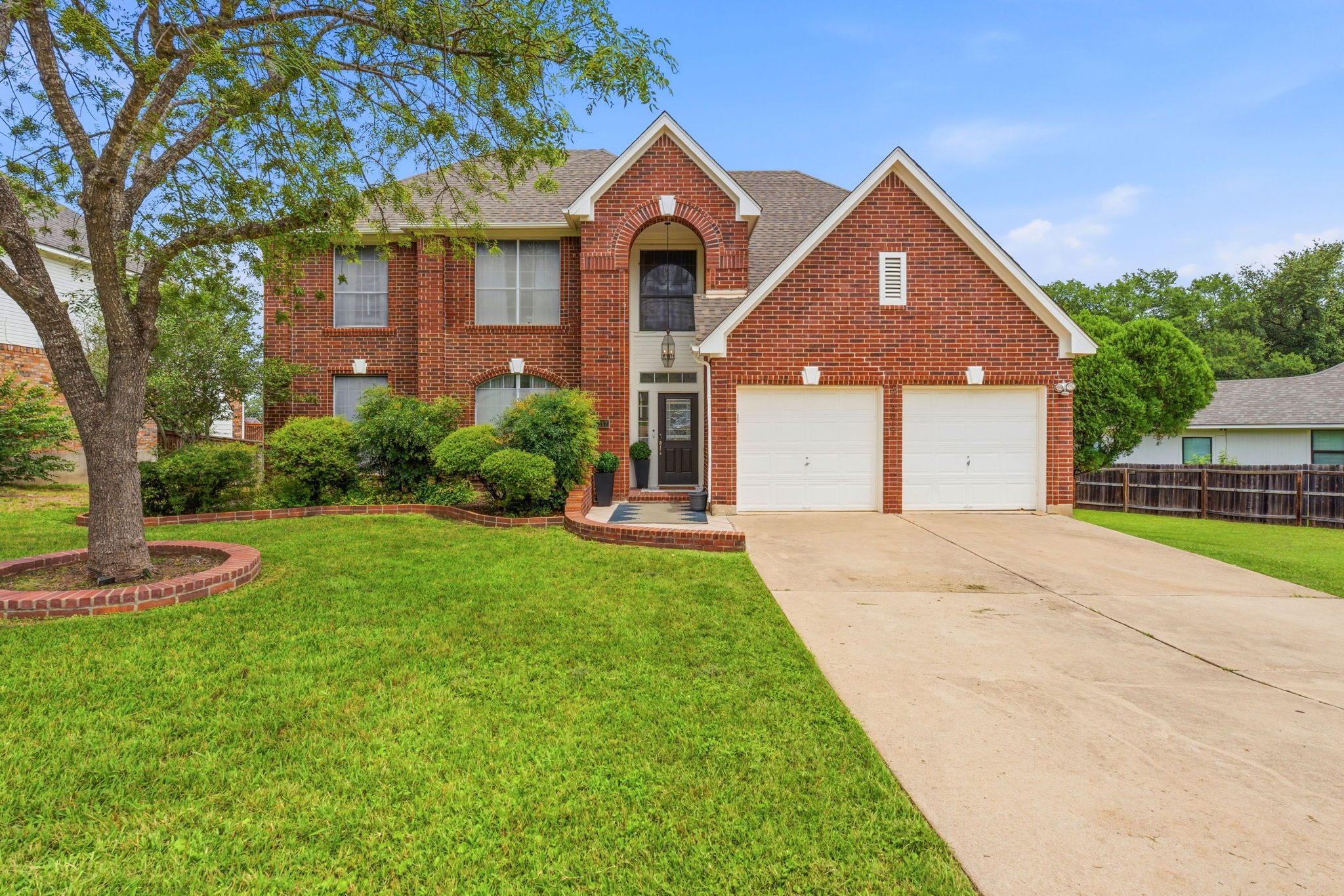 8317 Pommel Drive Austin, TX 78759 - Photo 2 of 26 A classic brick facade with an inviting arched entryway awaits, complemented by a neatly manicured lawn and mature landscaping.
