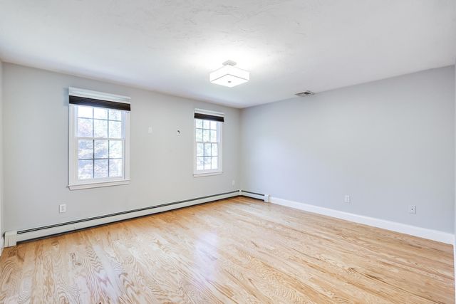 a view of empty room with wooden floor and ceiling fan