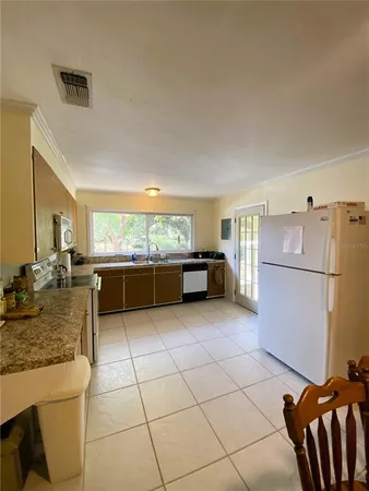 a kitchen with granite countertop a refrigerator and a stove top oven