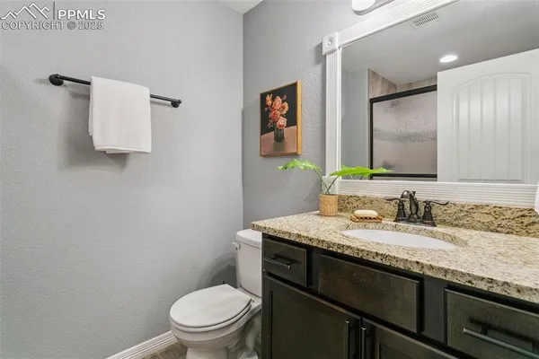 a bathroom with a granite countertop toilet sink and mirror