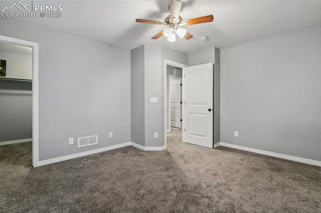 an empty room with closet and a ceiling fan