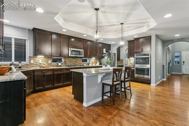a kitchen with stainless steel appliances kitchen island granite countertop wooden cabinets and a stove top oven