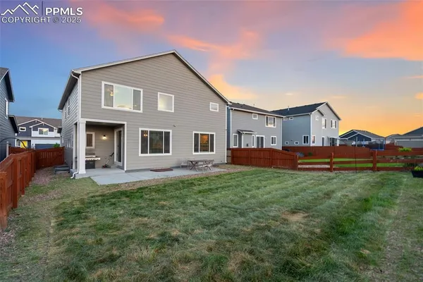 a view of a yard in front of a house with large windows