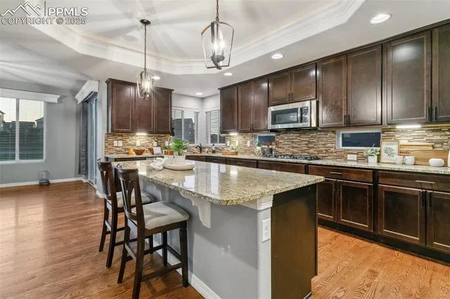 a kitchen with stainless steel appliances granite countertop wooden cabinets a stove a sink and a center island