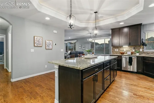 a kitchen with stainless steel appliances granite countertop a sink a counter space cabinets and wooden floor