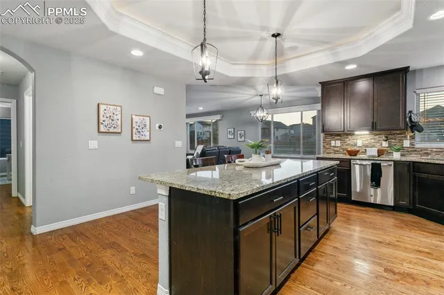 a kitchen with stainless steel appliances granite countertop a sink a counter space cabinets and wooden floor