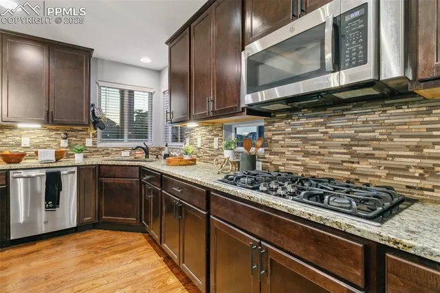 a kitchen with stainless steel appliances granite countertop a sink stove and cabinets