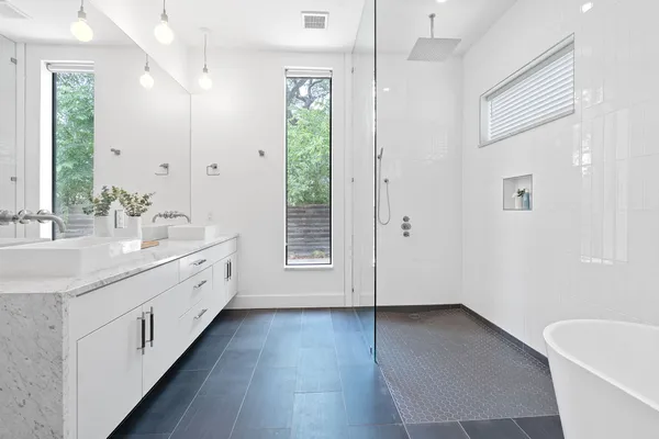 a bathroom with a white tub shower and windows