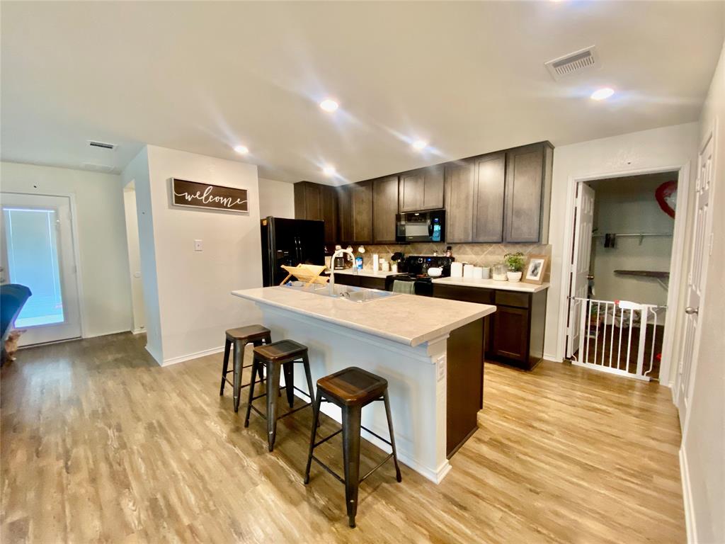 110 West Point Way Elgin, TX 78621 - Photo 6 of 19 A functional kitchen incorporates a central island, dark cabinetry, and recessed lighting over wood flooring.