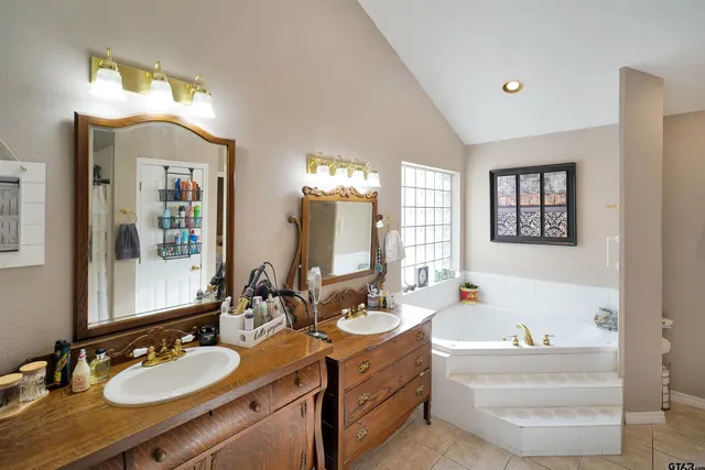 a bathroom with a sink double vanity granite tub and a mirror