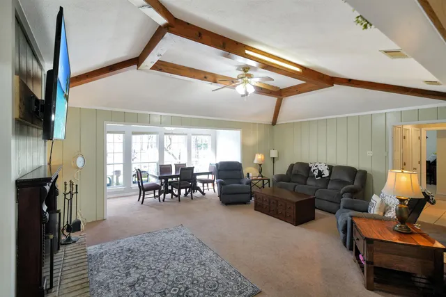 a living room with furniture a flat screen tv and floor to ceiling window