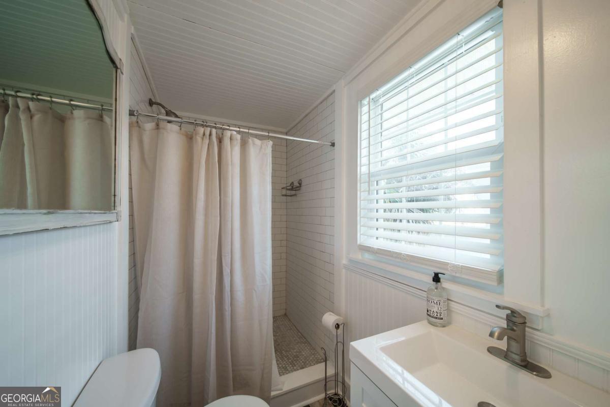 1413 2nd Avenue, Unit 2 Tybee Island, GA 31328 - Photo 22 of 30 a bathroom with a sink a toilet a shower and a window