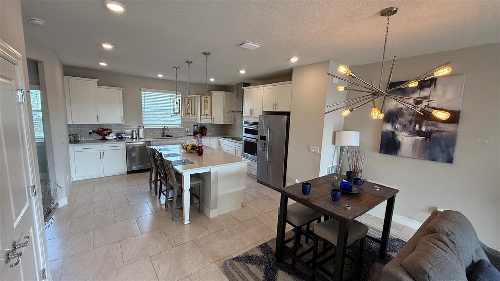 7718 Sweet Star Avenue Orlando, FL 32836 - Photo 26 of 51 a kitchen with stainless steel appliances kitchen island granite countertop a refrigerator a stove a sink dishwasher with a dining table and chairs