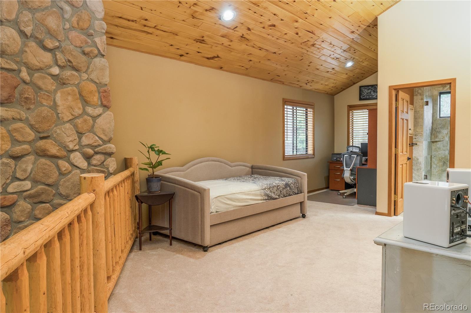 37 Juniper Court Evergreen, CO 80439 - Photo 23 of 44 a spacious bedroom with a bed and a table in it