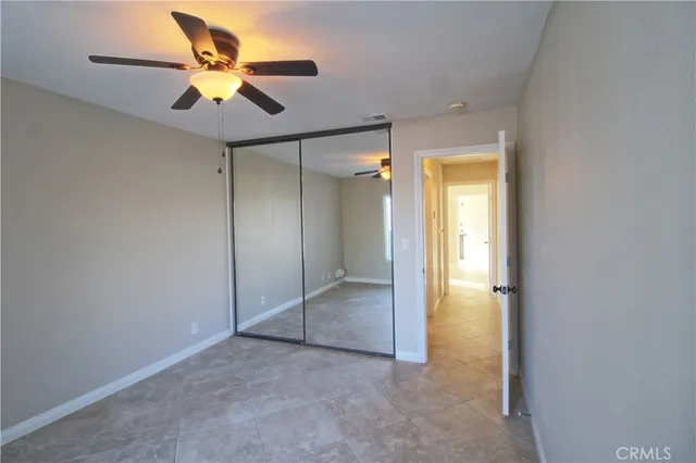 an empty room that has a large window and a chandelier fan