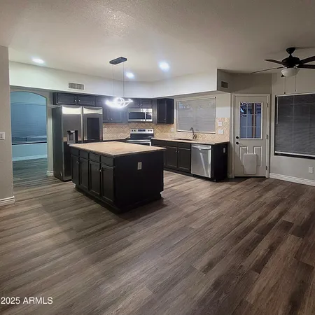 a large kitchen with stainless steel appliances granite countertop a large counter top and wooden floors