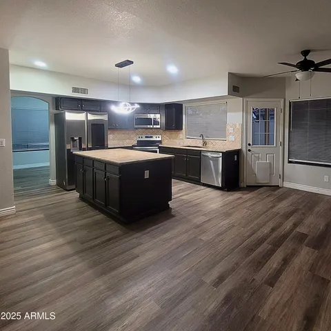 a large kitchen with stainless steel appliances granite countertop a large counter top and wooden floors