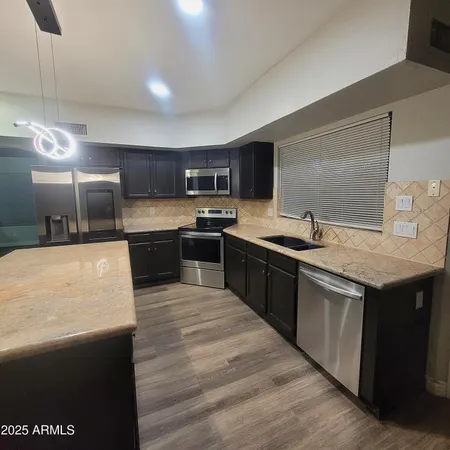 a large kitchen with stainless steel appliances wooden cabinets a sink and a stove