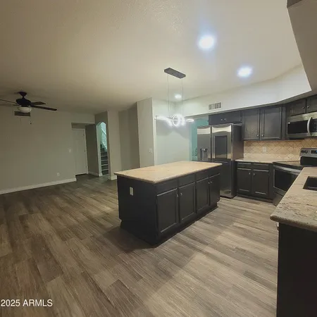 a large room with kitchen island a sink wooden floor and black appliances