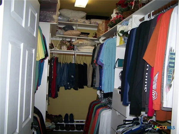 a view of walk in closet with clothes and shoes