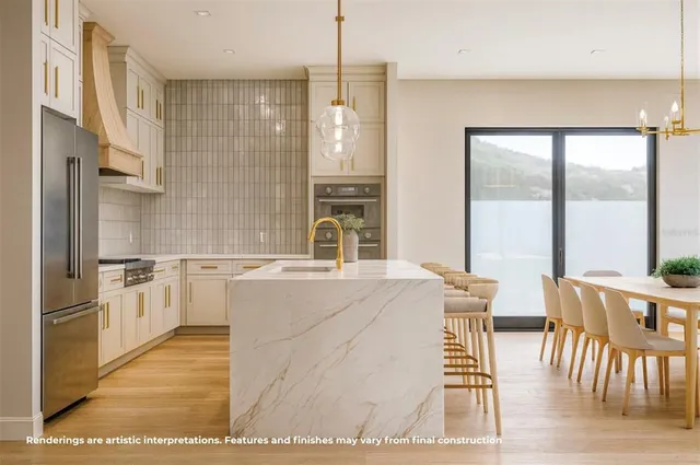 a kitchen with stainless steel appliances granite countertop a stove a refrigerator a dining table and chairs with wooden floor