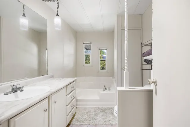 a bathroom with a granite countertop sink mirror and a bath tub