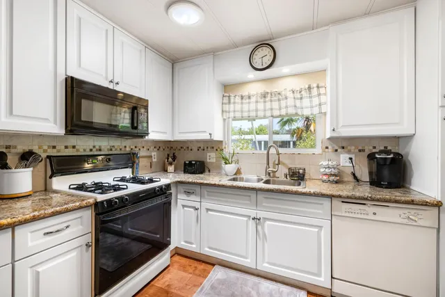 a kitchen with granite countertop white cabinets and stainless steel appliances
