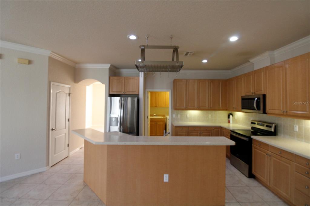 8476 Madrid Road Weeki Wachee, FL 34613 - Photo 19 of 37 a kitchen with stainless steel appliances kitchen island granite countertop a refrigerator a sink a stove top oven and a dining table with wooden floor