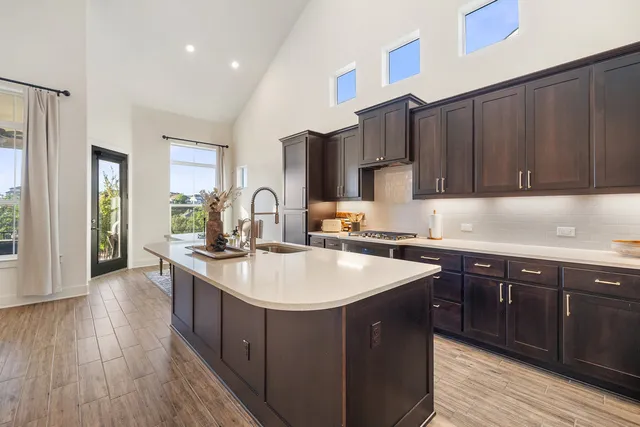 a kitchen with kitchen island granite countertop a sink stove and wooden cabinets