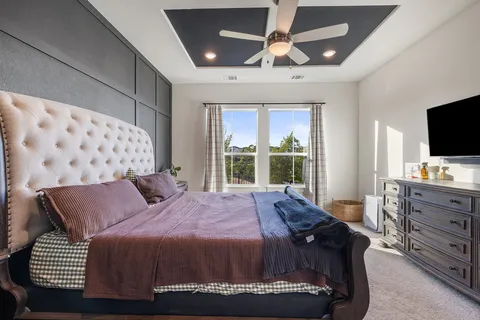 a bedroom with a bed and a flat tv screen on dresser