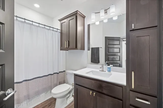 a bathroom with a sink a toilet a mirror and shower