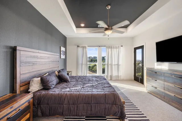 a bedroom with a large bed a flat tv screen and a dresser