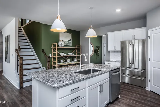 a kitchen with stainless steel appliances granite countertop a kitchen island hardwood floor sink stove and white cabinets