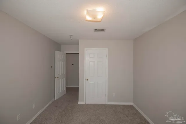 a view of an empty room with a chandelier fan