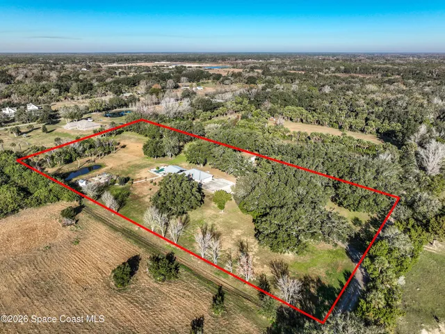 an aerial view of a house with a yard and lake view in back