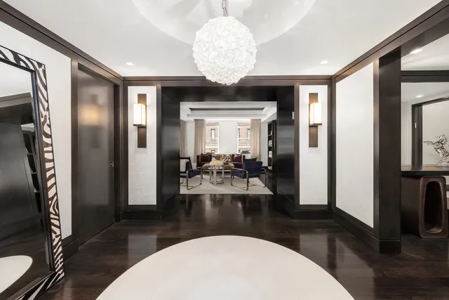 a view of a livingroom with furniture a fireplace wooden floor and a chandelier