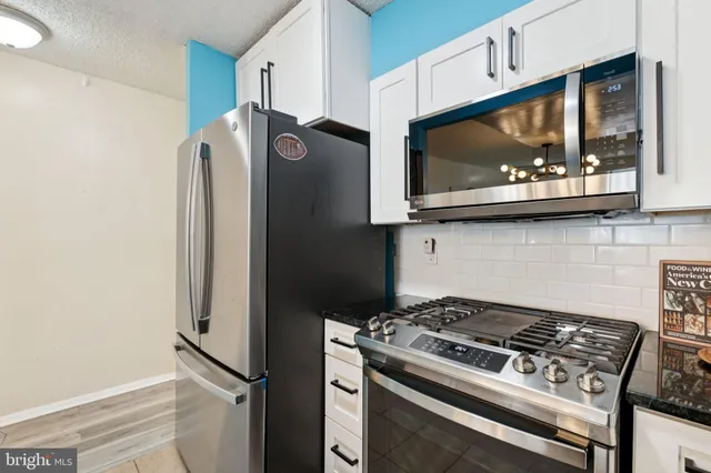 a kitchen with stainless steel appliances white cabinets and a stove top oven