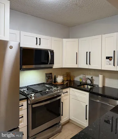 a kitchen with stainless steel appliances a stove a microwave a sink and cabinets
