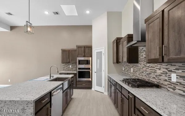 a kitchen with stainless steel appliances granite countertop a stove a sink and a refrigerator