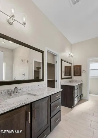 a bathroom with a granite countertop double vanity sink and mirror