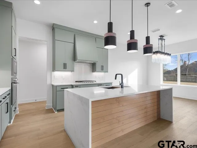 a kitchen with stainless steel appliances granite countertop a sink a stove and a refrigerator