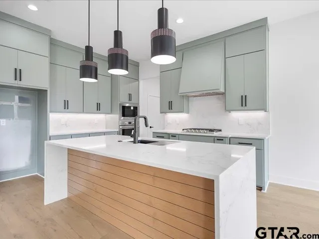 a kitchen with stainless steel appliances granite countertop a sink a stove and a refrigerator