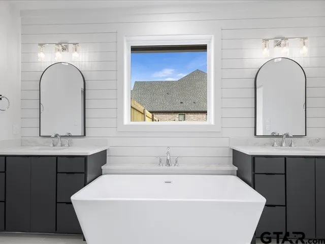 a bathroom with a tub a sink and mirror