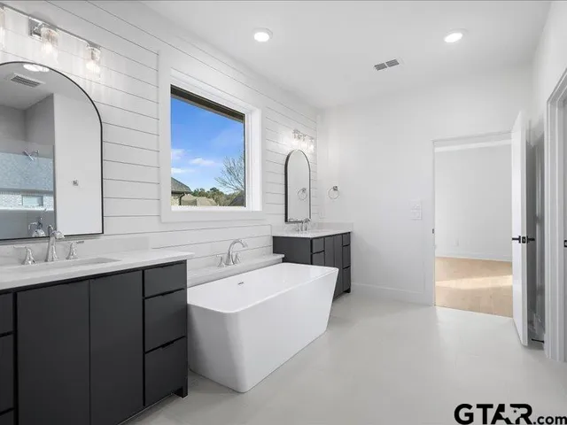 a bathroom with a sink a large mirror and a bathtub