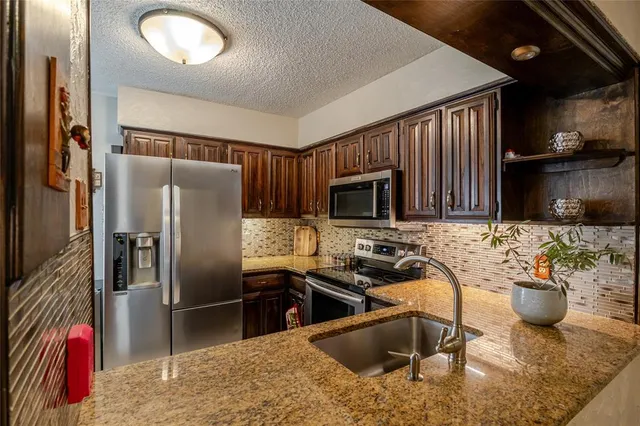 a kitchen with stainless steel appliances granite countertop a sink refrigerator and microwave